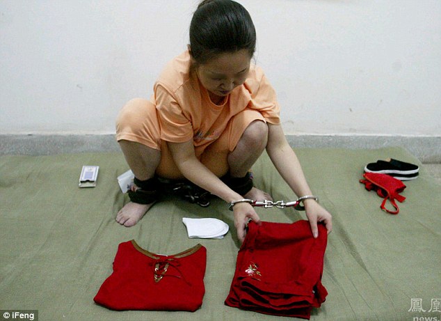 Ms Donggui, in handcuffs and ankle shackles, neatly folds her red clothes onto the mattress she'll sleep on before she's shot in the morning 