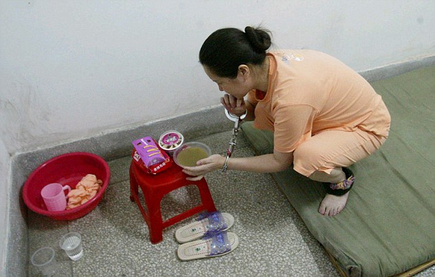 Her last meal: Ms Donggui picks up a bowl of green bean soup on a red stool, that also has McDonalds fries, a burger and ice cream on