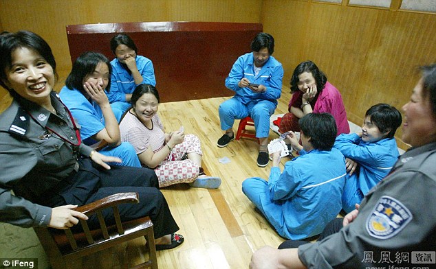 Ms Xiuling and Ma Qingxiu, both sentenced to die, play cards with other inmates as guards look on. The group appear relaxed and upbeat 